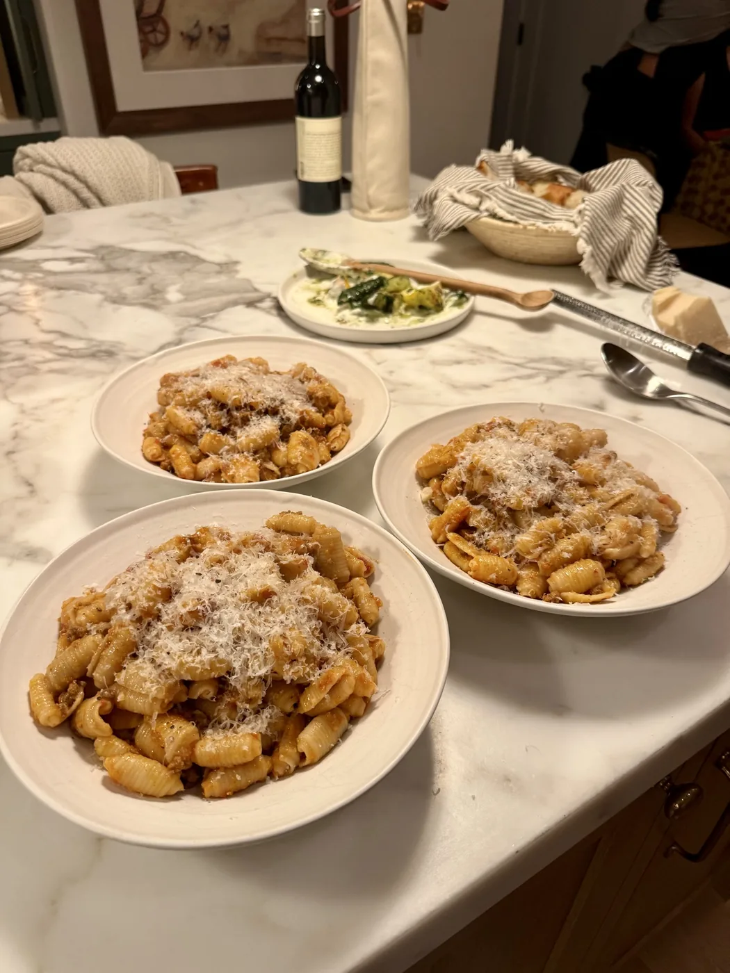 Three plates of pasta with beef bolognese and grated cheese